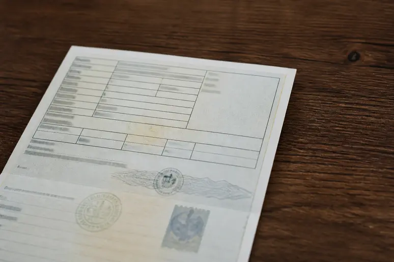 Une carte grise française officielle est posée sur une table en bois, mettant en évidence l'absence d'informations sur le code couleur du véhicule.
