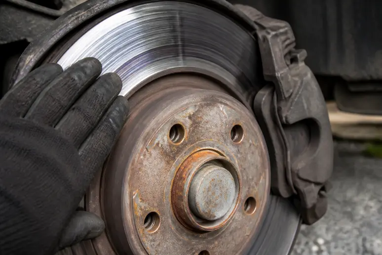 Des rayures profondes et une légère décoloration bleue sur un disque de frein de voiture, signalant une usure significative nécessitant un remplacement.