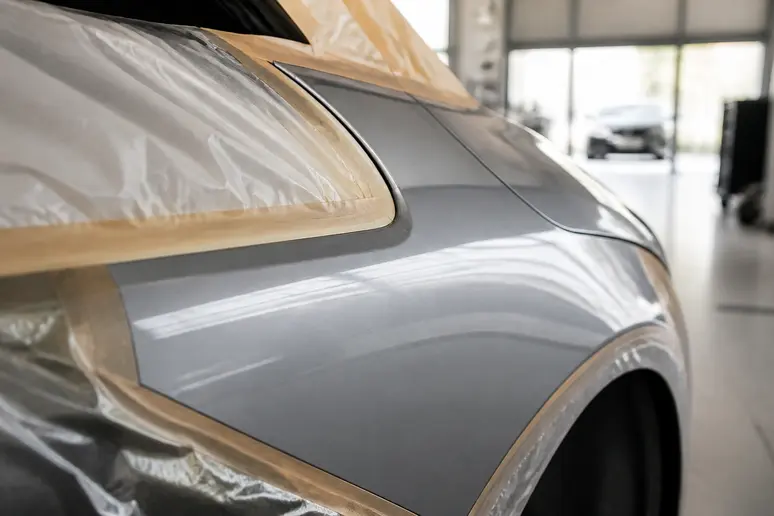 Vue rapprochée d'une carrosserie de voiture avec une retouche de peinture réussie, démontrant l'importance d'une application soignée et protégée.