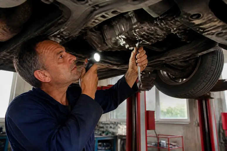 Un mécanicien français examine la transmission d'un Kia Sorento 2.5 CRDi dans un garage, soulignant les points critiques à vérifier.