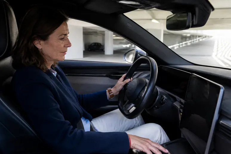 Une conductrice française examine l'autonomie restante sur l'écran de sa voiture électrique dans un parking souterrain.