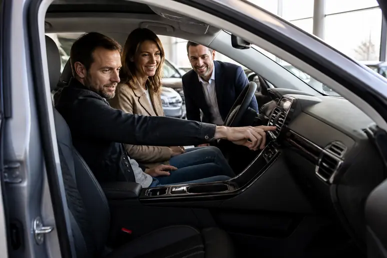 Couple examinant un SUV d'occasion chez autosphere nantes, avec un vendeur expliquant les options.