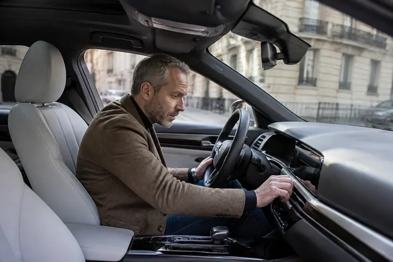 Homme vérifiant les caractéristiques d'une berline moderne pour devenir chauffeur VTC.