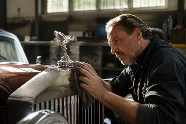 Un mécanicien français nettoie méticuleusement le logotipo rolls royce sur une Rolls-Royce ancienne.