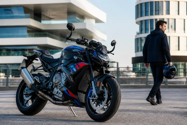 La BMW M1000R, moto sportive sur route asphaltée, un motard à l'arrière plan, lumière naturelle.