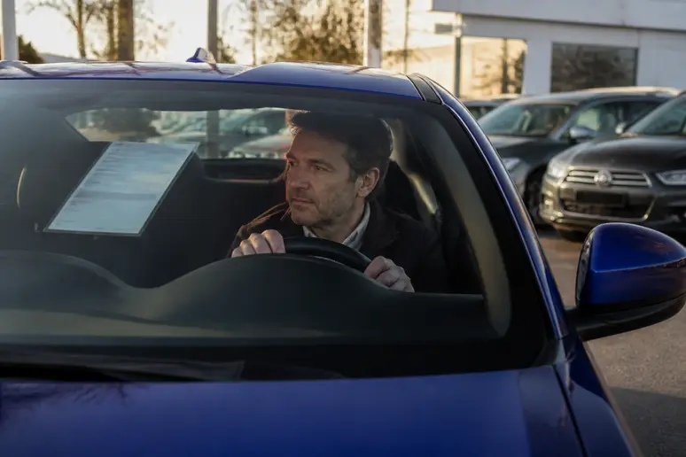 Homme français examine le prix d'une Subaru BRZ d'occasion en concession.