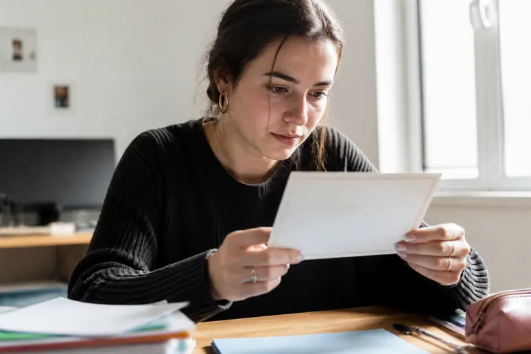 Une jeune femme examine un certificat officiel mentionnant la date de réussite de son épreuve théorique du code de la route.