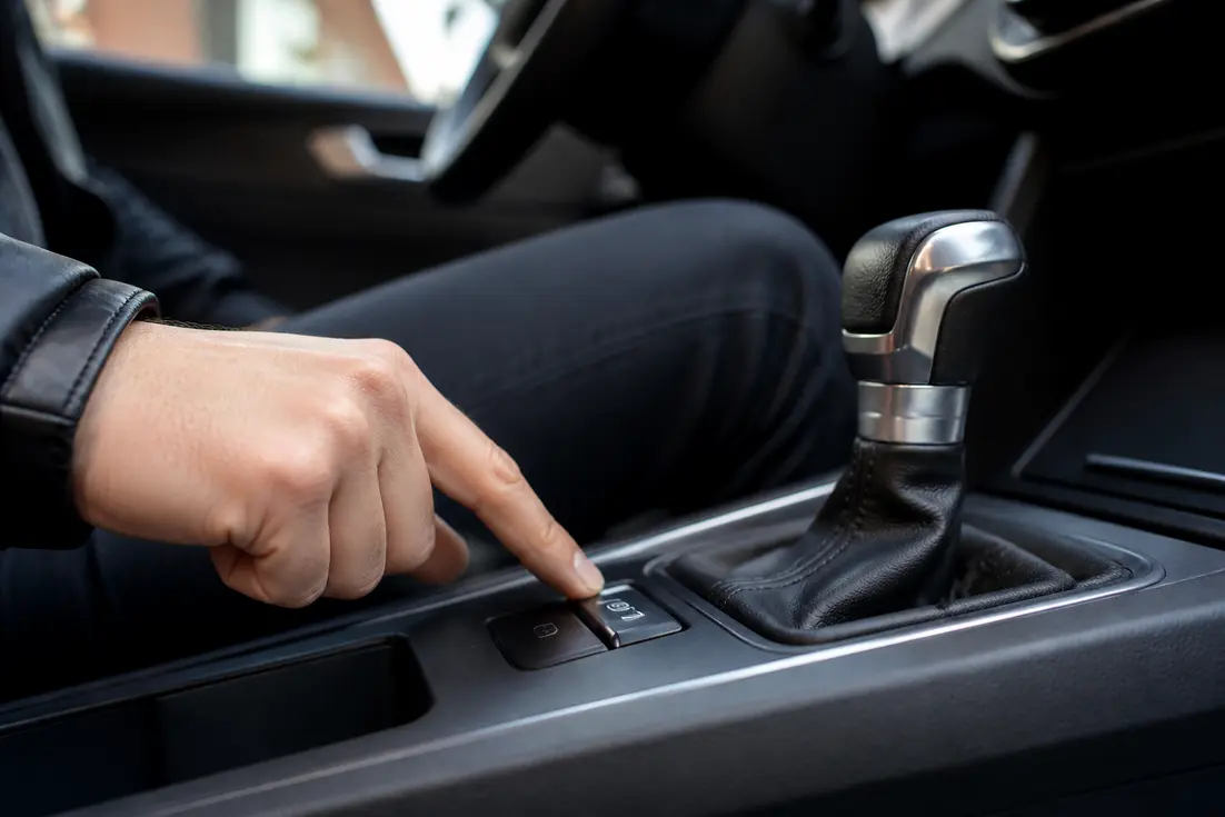 Conducteur actionnant le bouton Auto Hold fonctionnement sur la console centrale d'une voiture moderne