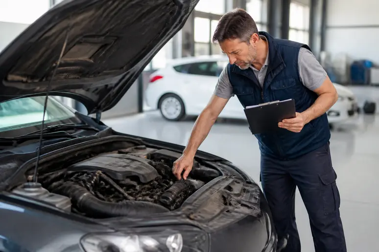Un mécanicien examine le compartiment moteur d'une voiture d'occasion pour vérifier l'état général avant la vente