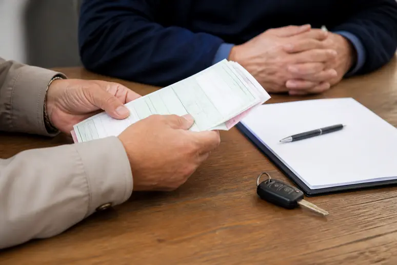 Examen attentif des documents administratifs et de la carte grise d'un véhicule d'occasion sur une table