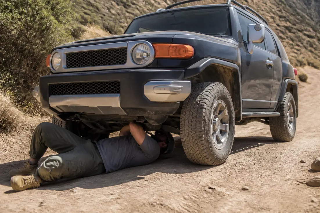Un Toyota FJ Cruiser caractéristiques usage garé sur un chemin de terre lors d'une inspection mécanique.