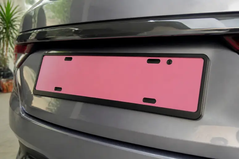 Plaque W garage rose avec caractères noirs fixée à l'arrière d'un véhicule