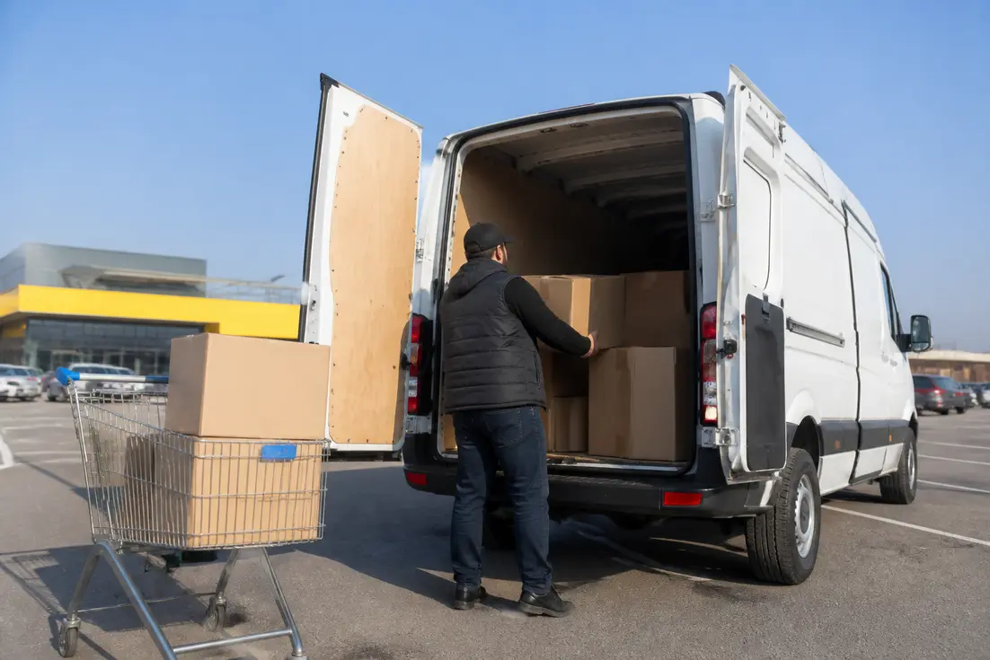 Un client charge des cartons à l'arrière d'un utilitaire loué avec Super U tarifs location véhicule