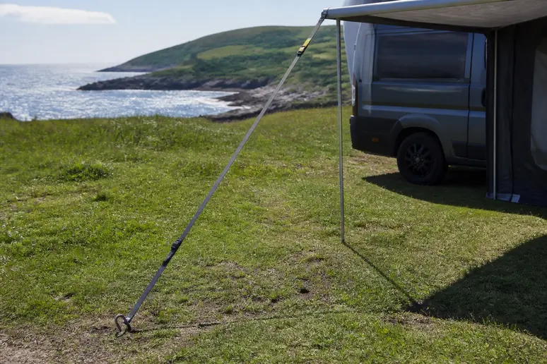 Sangle anti-tempête fixée en diagonale pour stabiliser l'auvent au sol