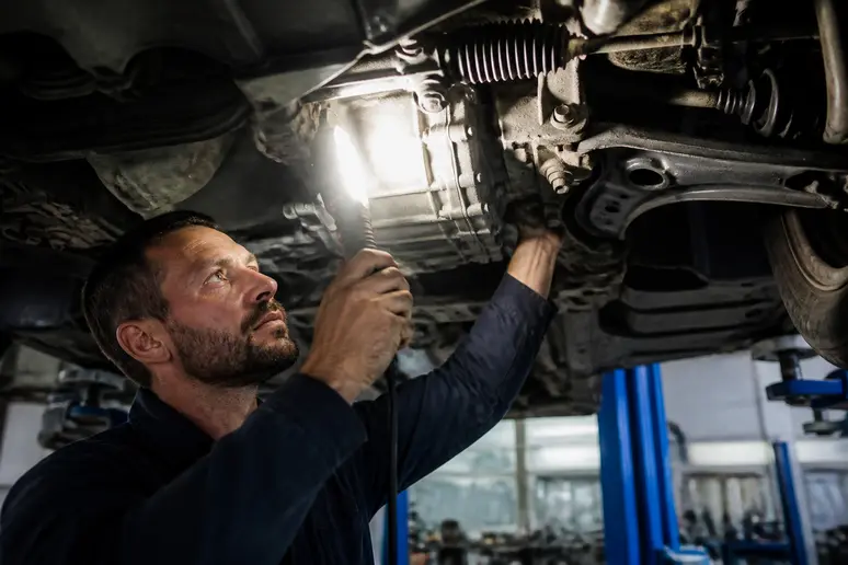Contrôle des éléments de transmission sous un véhicule sur pont élévateur.