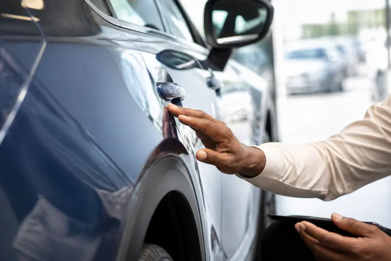 Inspection minutieuse de la carrosserie d'un véhicule d'occasion lors de sa livraison