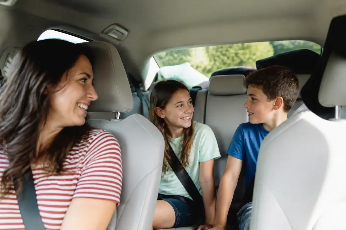 Famille heureuse en train de discuter joyeusement lors d'un jeu à faire en voiture sans écran.