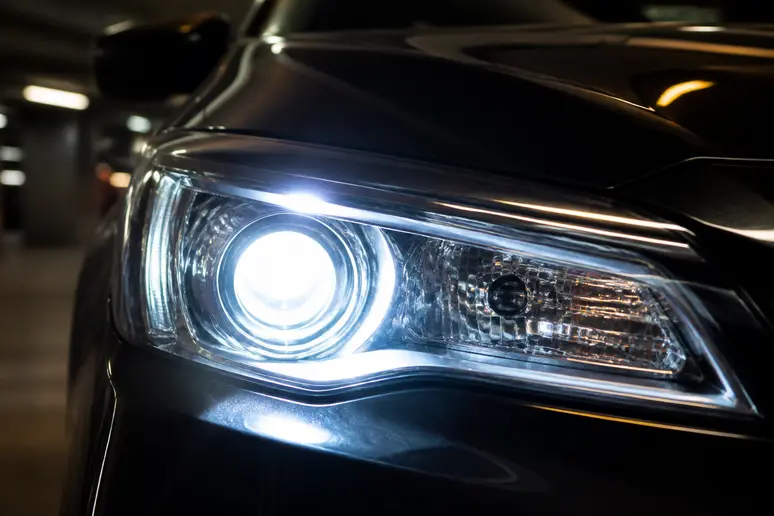 Gros plan sur un bloc optique de voiture allouant un faisceau xénon puissant dans un atelier.