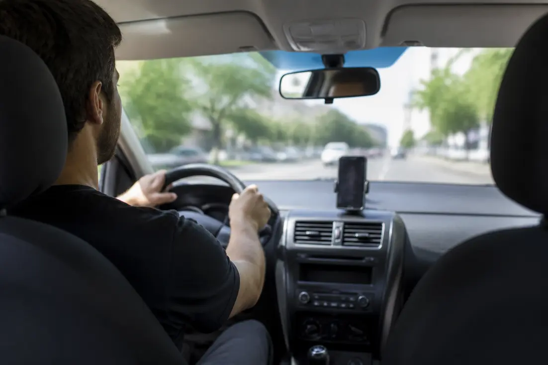 Un conducteur concentré sur la route avec son smartphone fixé sur le tableau de bord pour un Radarbot avis