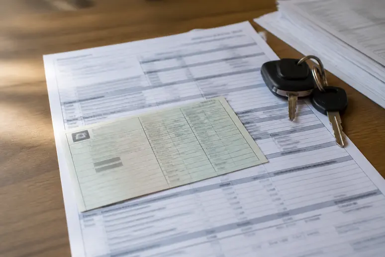 Documents administratifs et certificat d'immatriculation d'une automobile posés sur un bureau en bois.