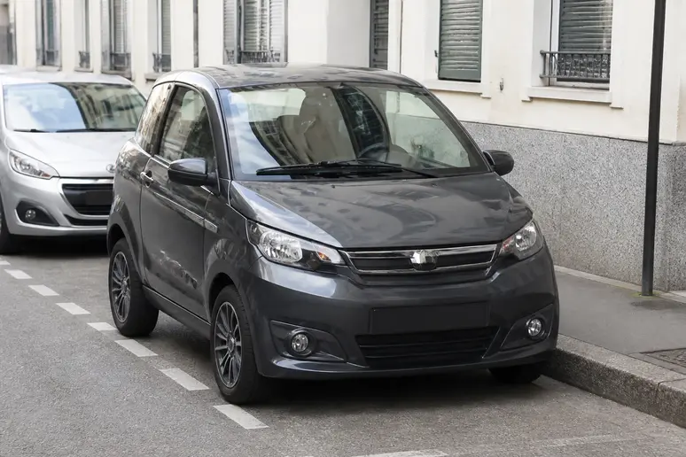 Voiture sans permis Aixam City garée le long d'un trottoir en ville.