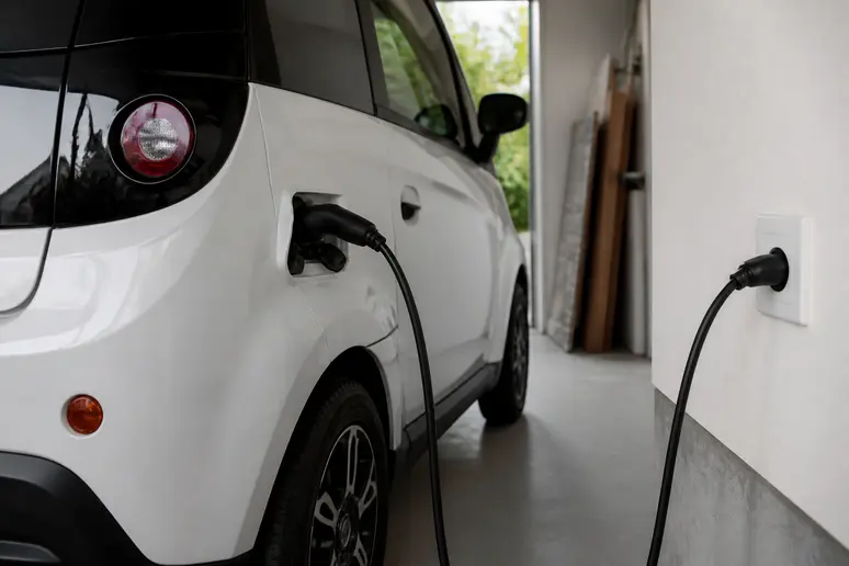 Câble de recharge d'une voiture sans permis branché sur une prise domestique.