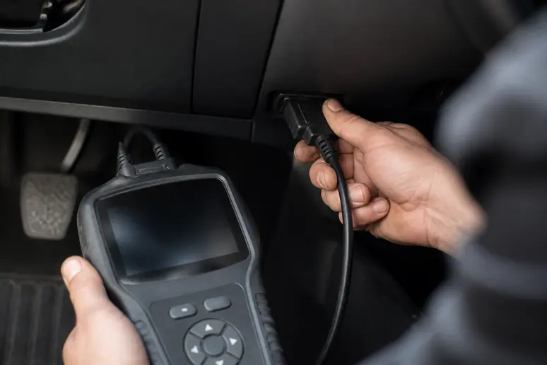 Technicien effectuant un diagnostic électronique précis pour l'entretien de la voiture