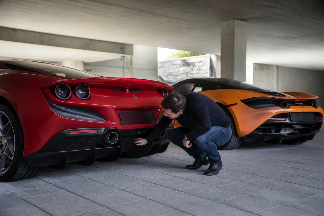 Comparatif Ferrari F8 Tributo McLaren 720S montrant les supercars garées dans un parking souterrain.