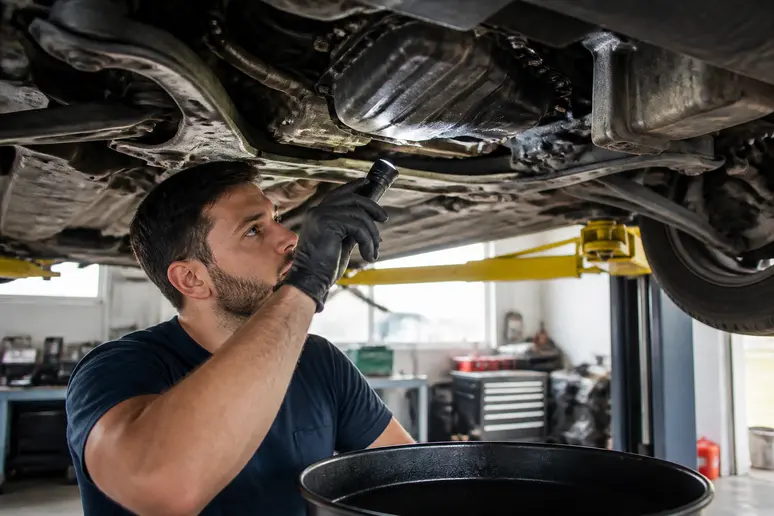 Contrôle d'un suintement d'huile sous un carter moteur lors de l'inspection technique
