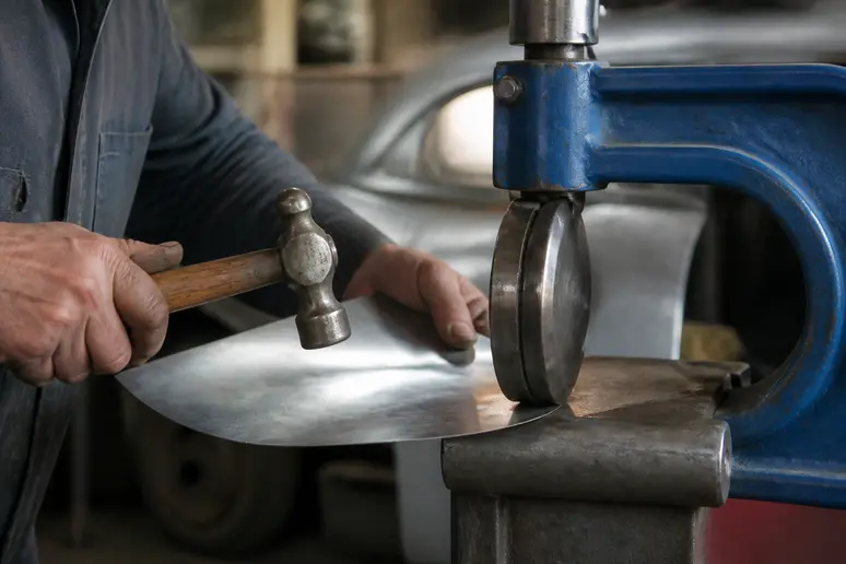 Mains d'un mécanicien façonnant une pièce métallique sur un outil traditionnel en atelier.